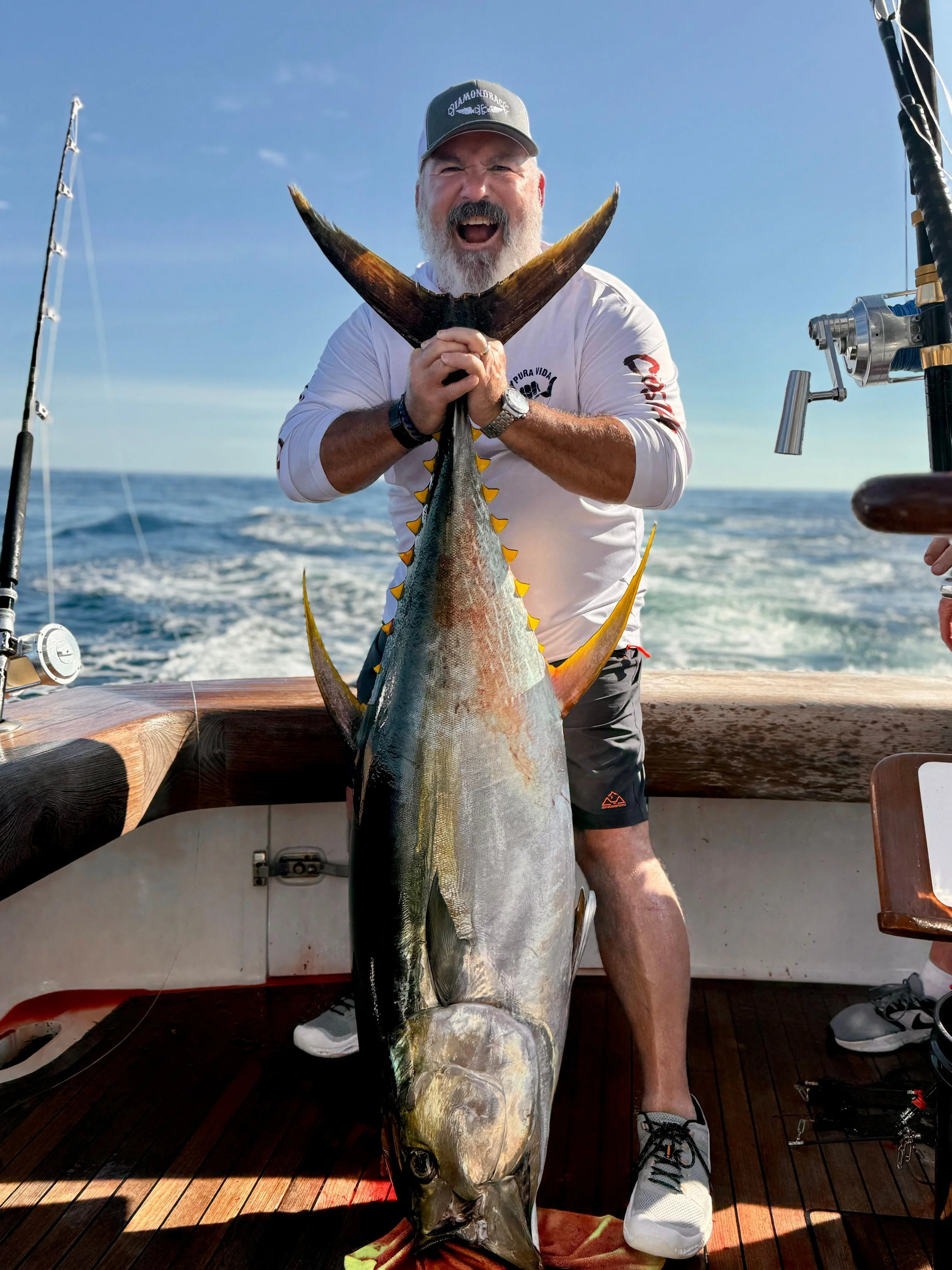 Man holding up a yellowfin tuna he caught.