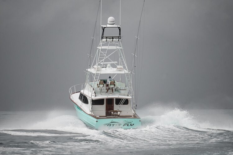 A boat speeding through the water on a cloudy day, creating a wake behind it.