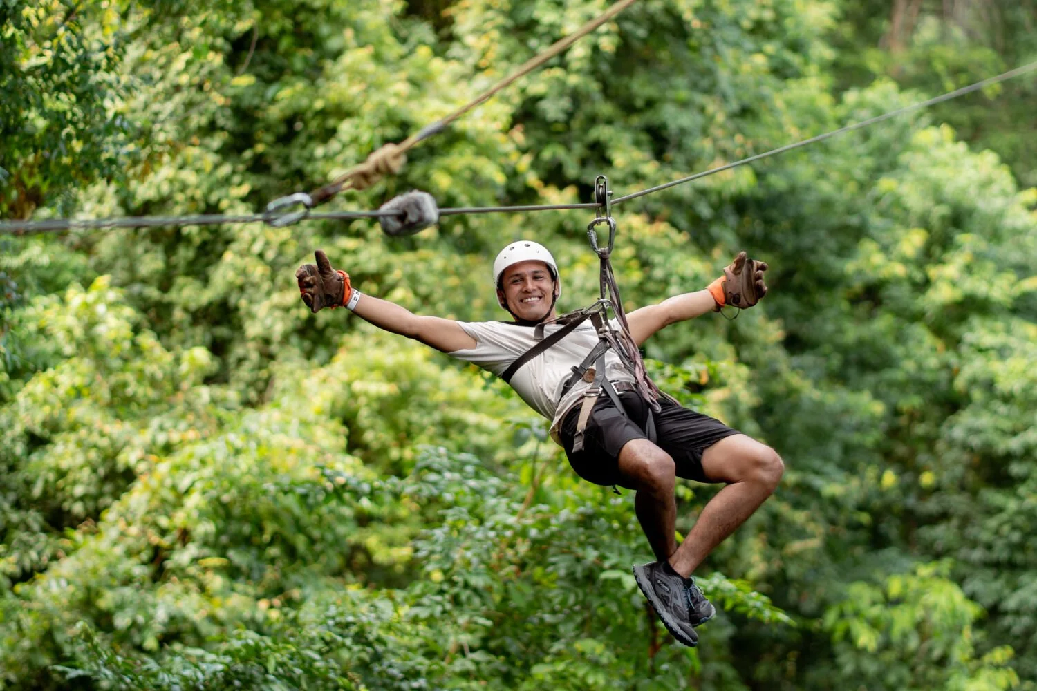 Man zip lining in Costa Rica, on cable, suspended above the trees.