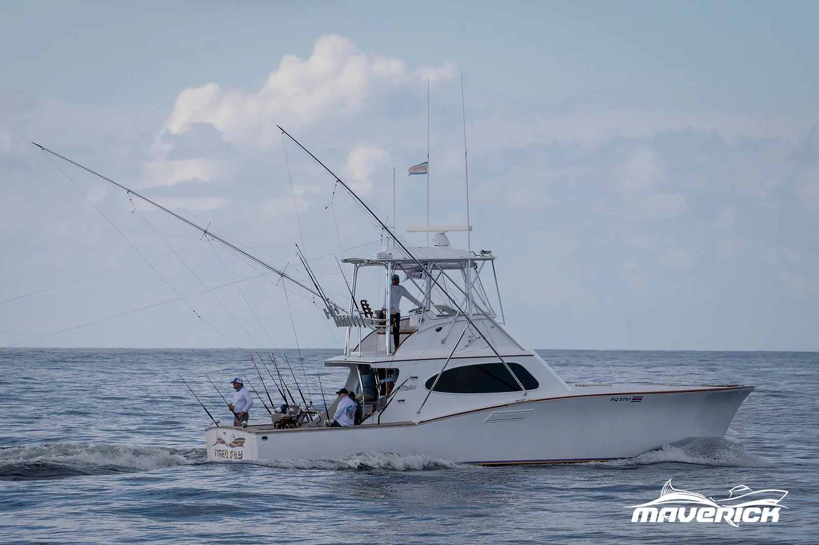 A white fishing boat with three men on board, two of whom are fishing, moving across calm ocean water under a partly cloudy sky, with the brand name 'Maverick' on the hull.