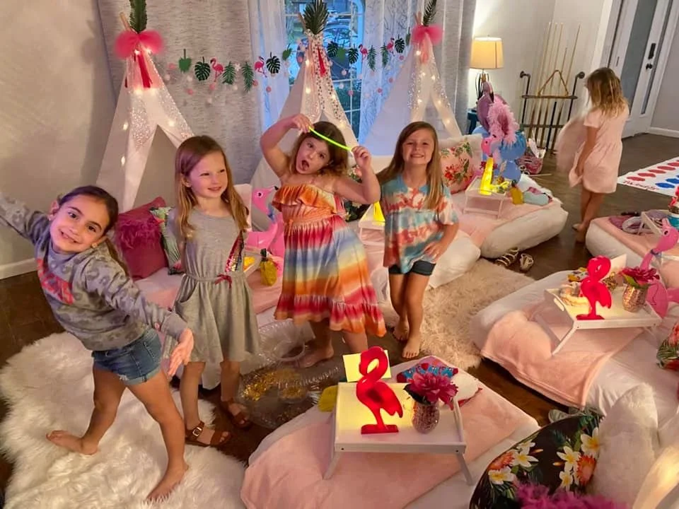Colorful birthday decorations featuring black, red, yellow, and green balloons, a large white balloon with birthday message, and themed décor with black and white checkered patterns in a living room.