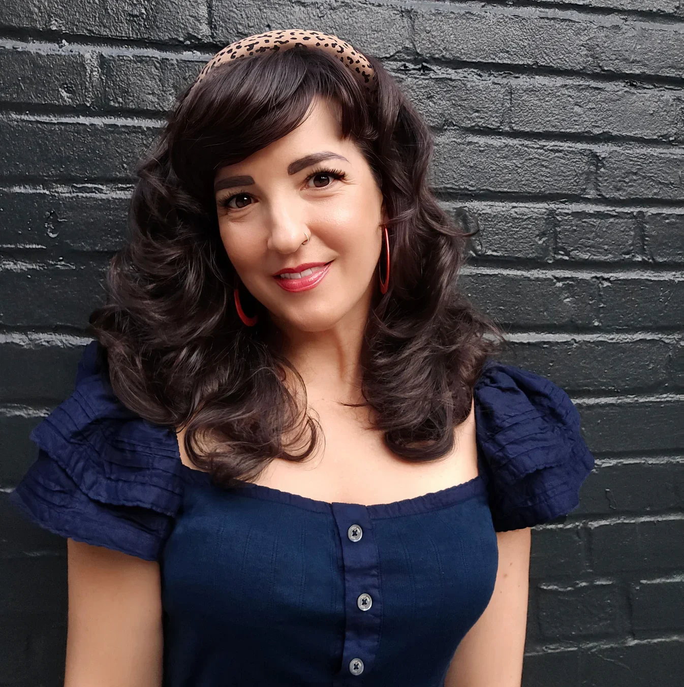 photo of author Erica Miriam Sabri in front of a black, brick wall