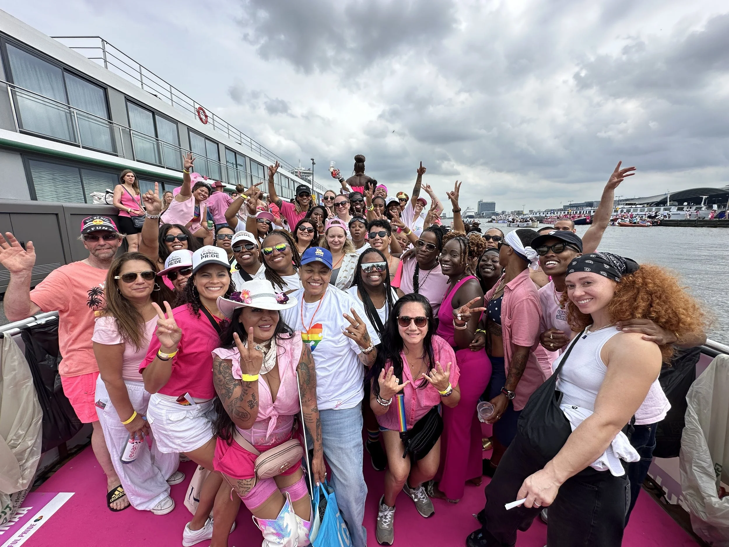 Lesbian travelers celebrating Amsterdam Pride canal boat parade in pink with Ladies Touch