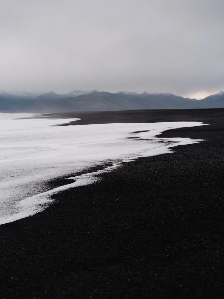 Weisse Wellen auf schwarzem Sand in Island