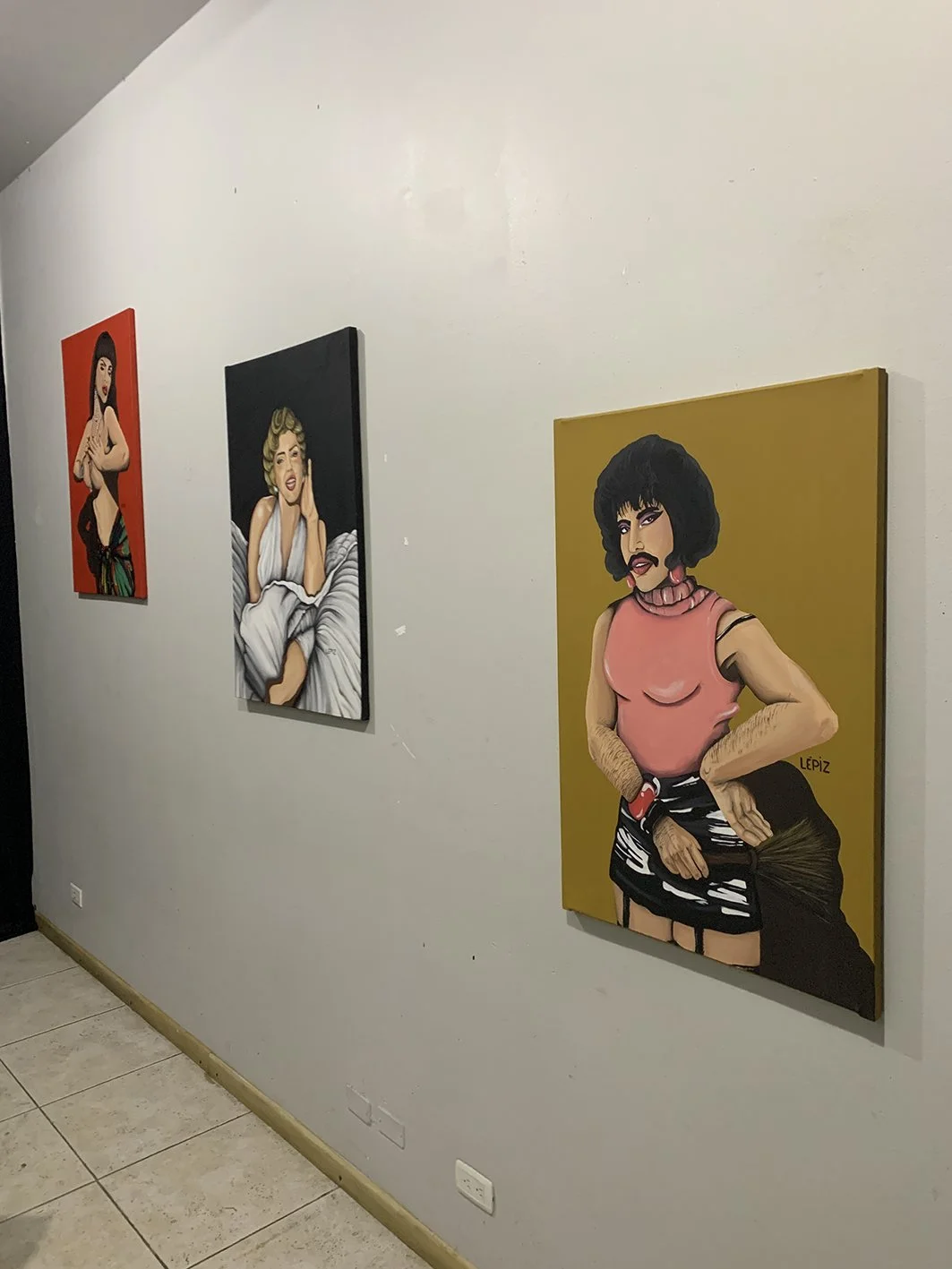 Cuatro pinturas de estilo retro en la pared, que representan retratos de mujeres con diferentes estilos y expresiones.
