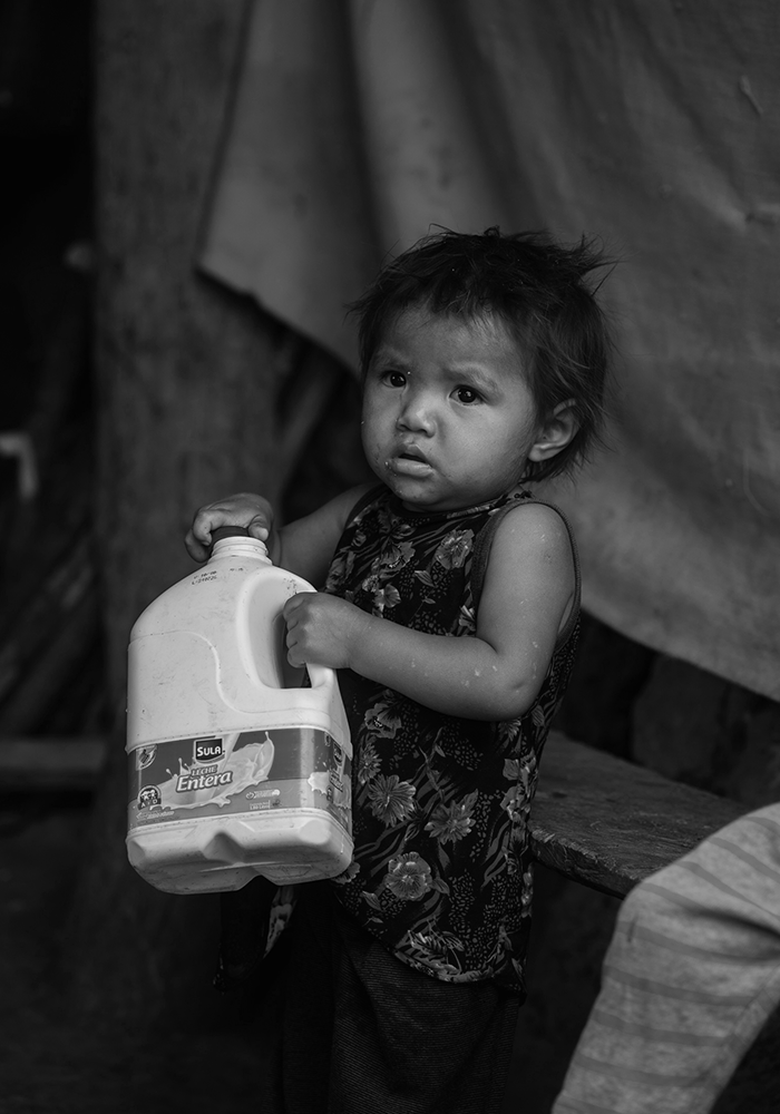 A young child carrying a plastic container used to collect water for the family.