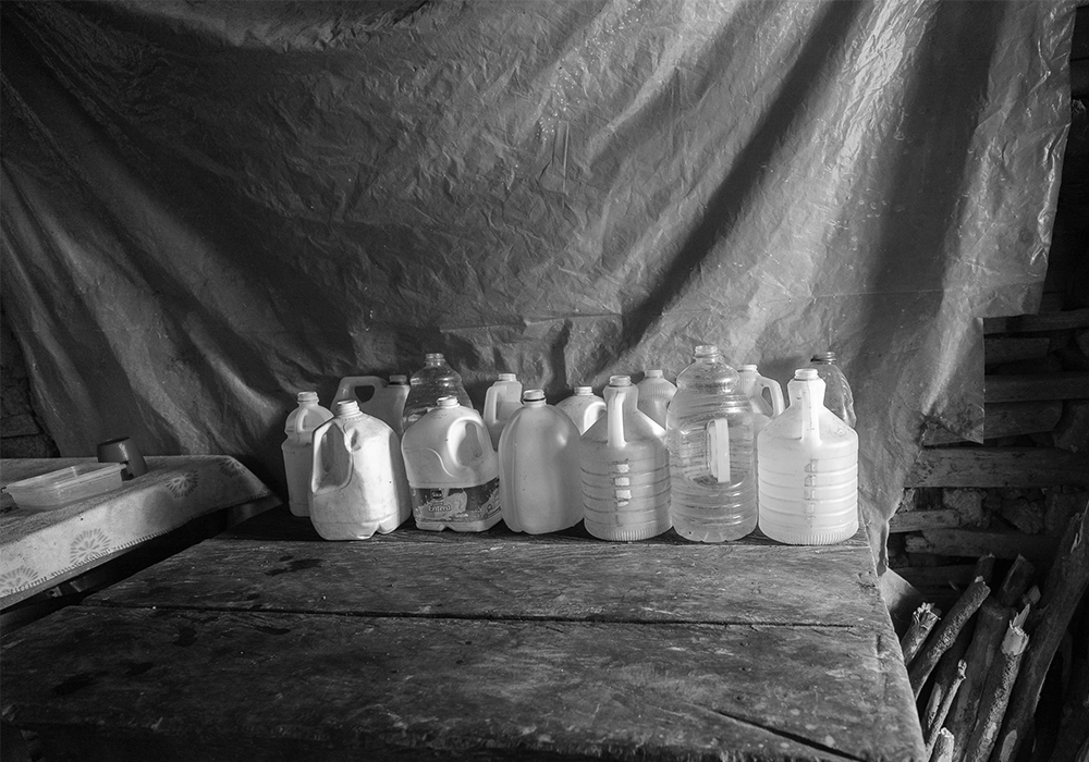 Reused plastic containers holding water inside a rural family home.
