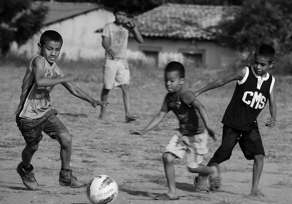 Young children playing soccer together during a community game in Honduras