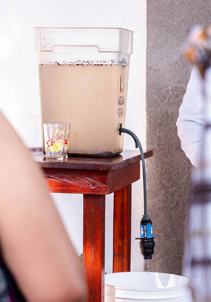 An Agua Pura filtration system dispensing clean drinking water inside a family home.