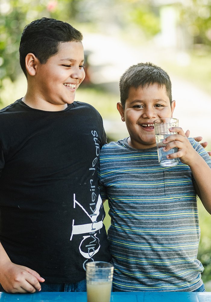 Two children drinking clean water provided through Serve Hope’s Agua Pura filtration program.