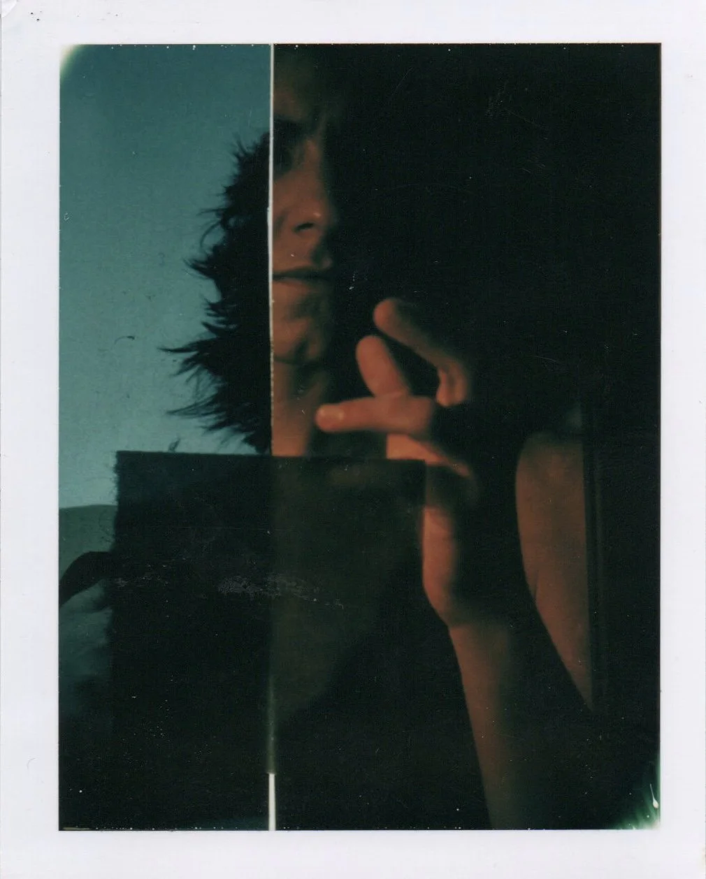 A person taking a mirror selfie with a phone, half of their face visible, with messy hair, wearing a sleeveless top, making a peace sign with their hand. The reflection is divided into multiple segments, creating a collage effect.