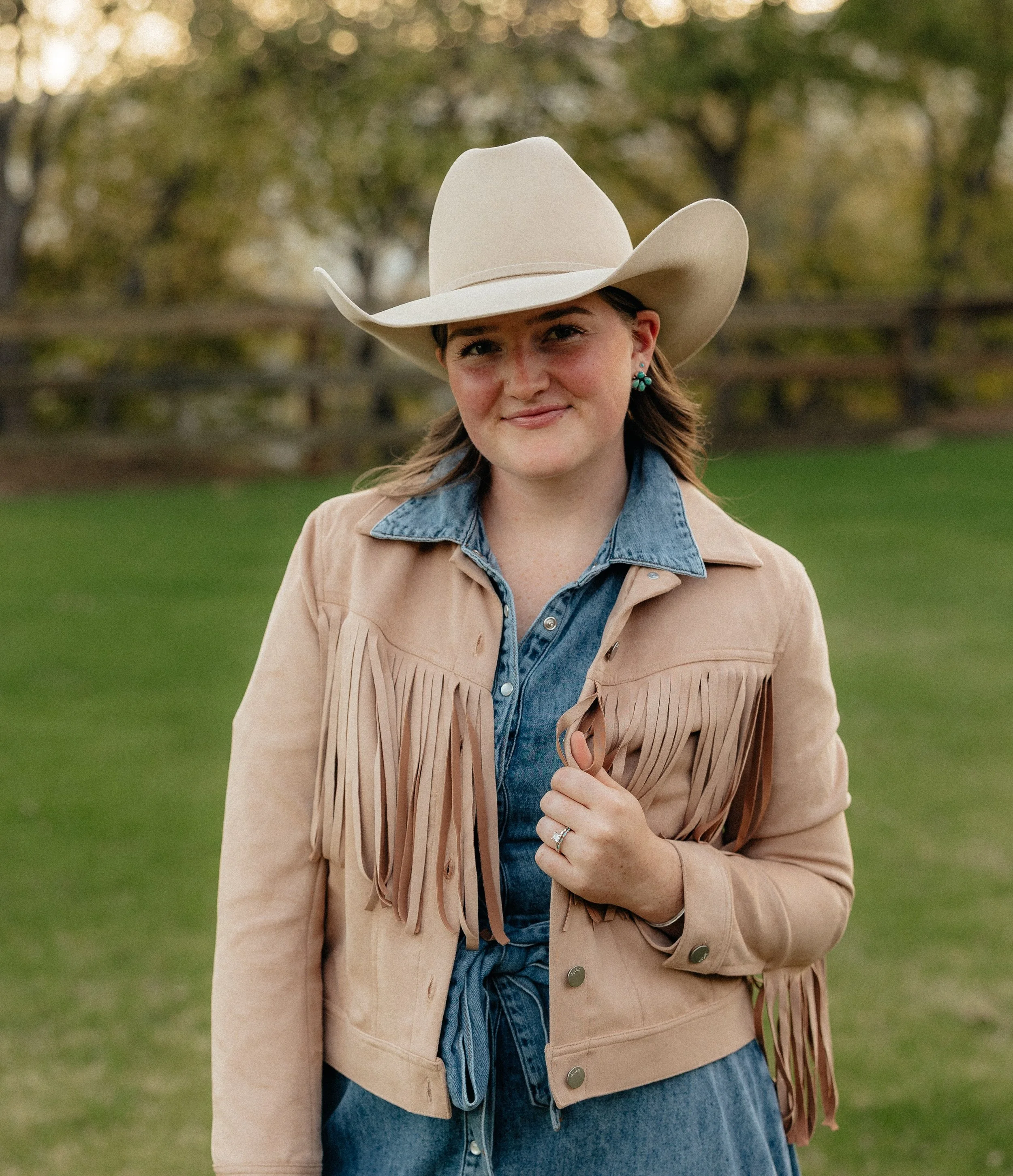 A women smiling in a cowboy hat and posing for a headshot