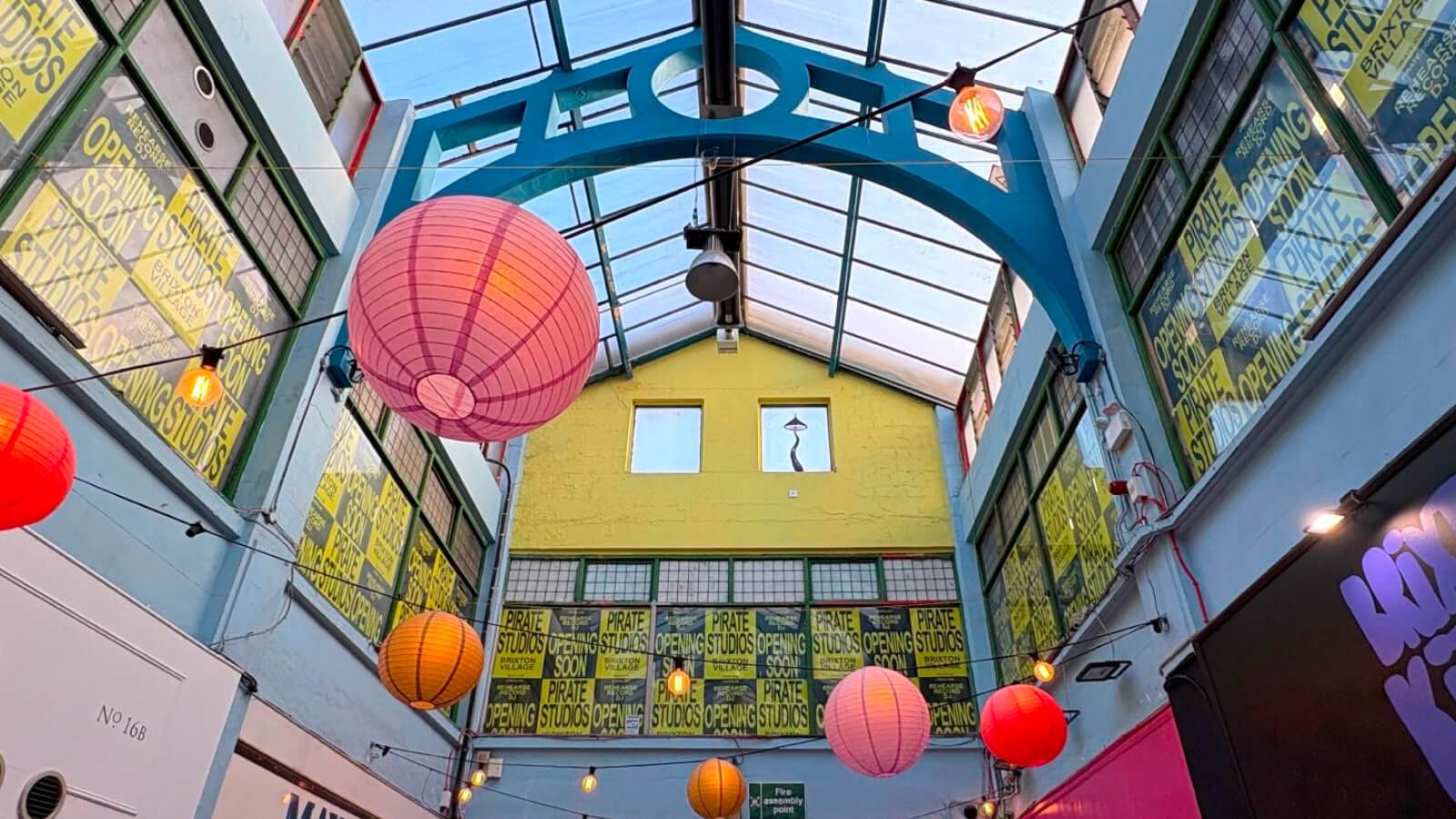 Exterior of the new Pirate Studios location in Brixton Village South London featuring colourful lanterns and glass roof.
