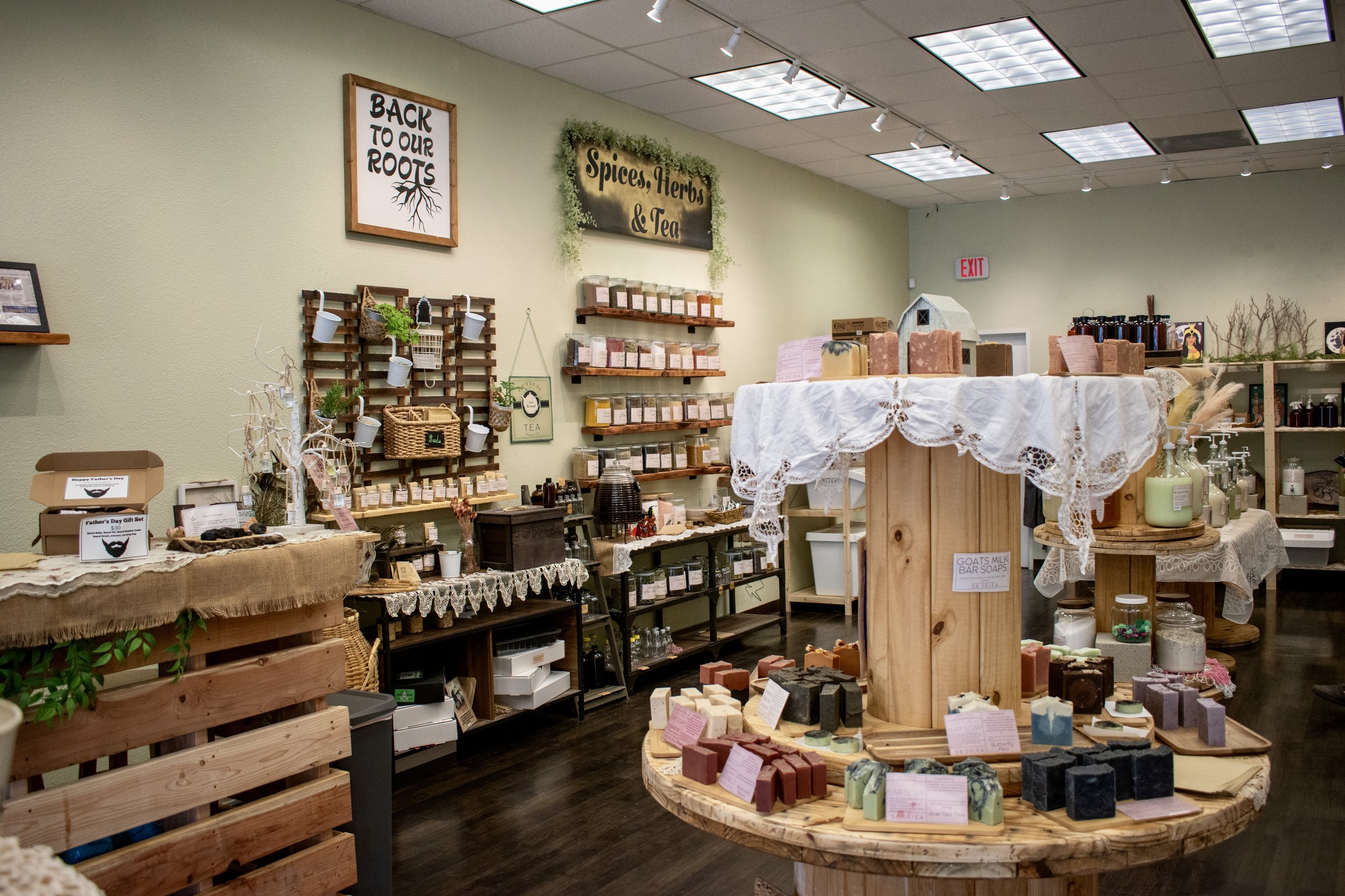 Interior of a store selling spices, herbs, tea, and handmade soaps, with shelves and tables displaying various products.