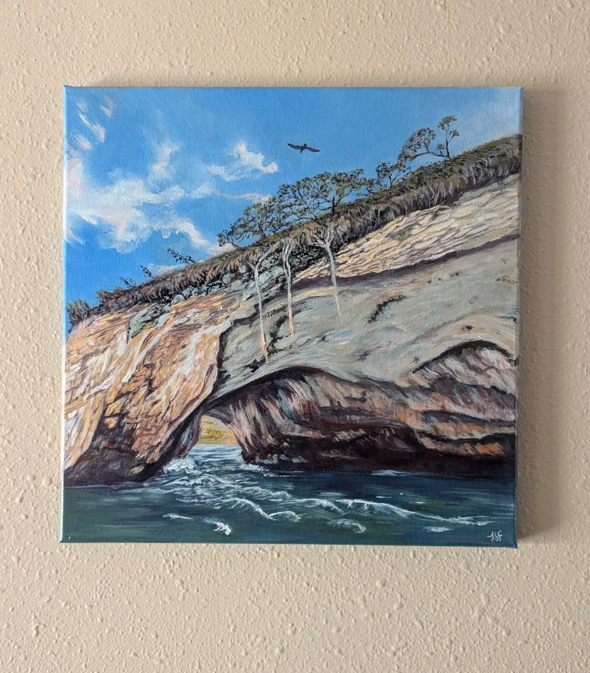 Acrylic painting of an arched rock formation from Los Arcos De Mismaloya marine park, near Puerto Vallarta, Mexico, on a sunny afternoon. Deep turquoise waves crash against the rocks and a sea bird soars over the top of the small island.