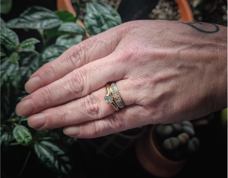 EverDearのメモリアルダイヤモンドをあしらったゴールドリングを身につけた手が、鉢植えの植物にそっと触れている。