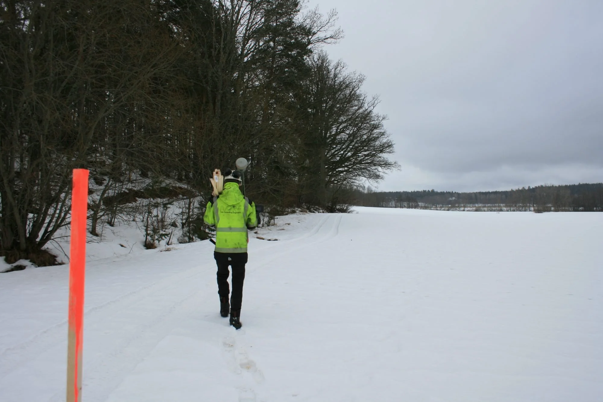 Person i snötäckt landskap vid markeringsstolpe