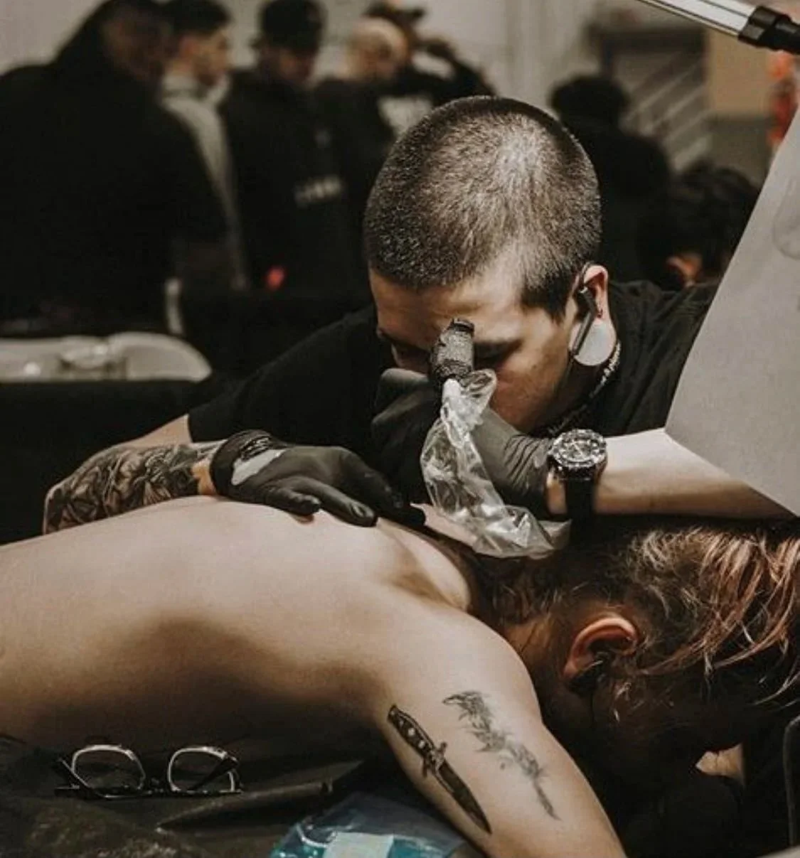 Tattoo Artist The Suit of Swords tattooing a blackwork back piece at a tattoo convention