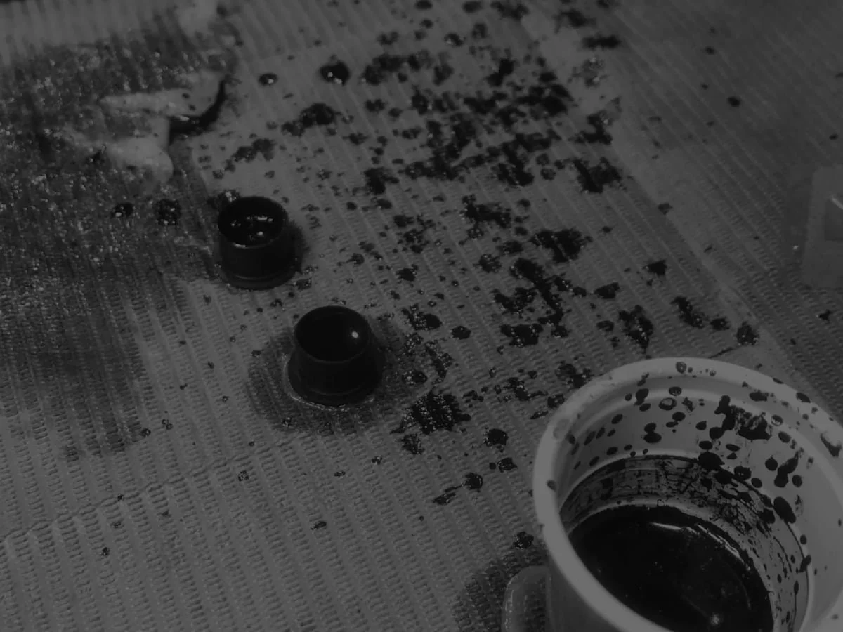 Black jars of tattoo ink on paper towels with ink stains.