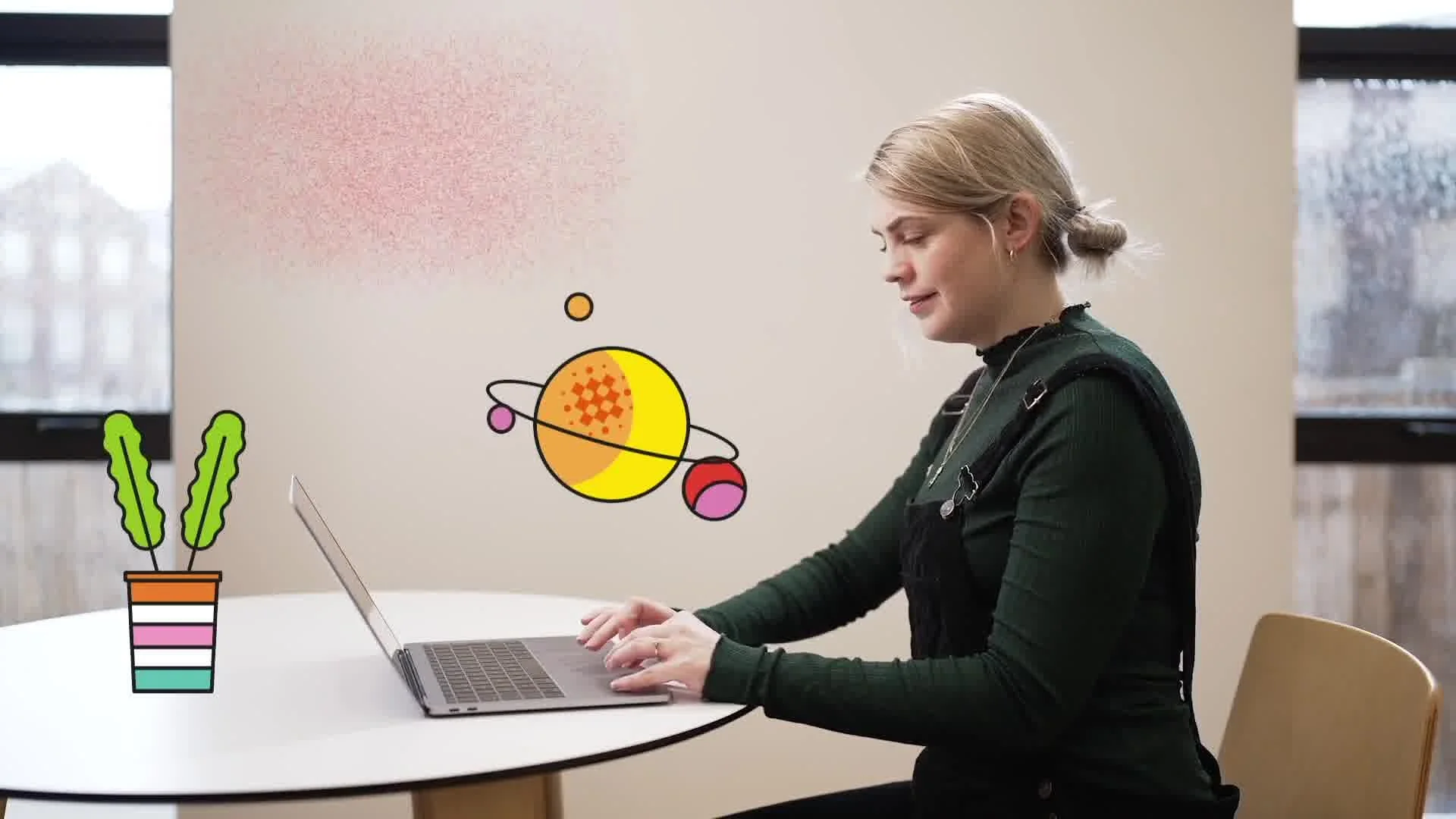 A woman sitting at a white table working on a laptop, with colorful cartoon drawings of a plant in a pot and an abstract planetary system floating nearby.