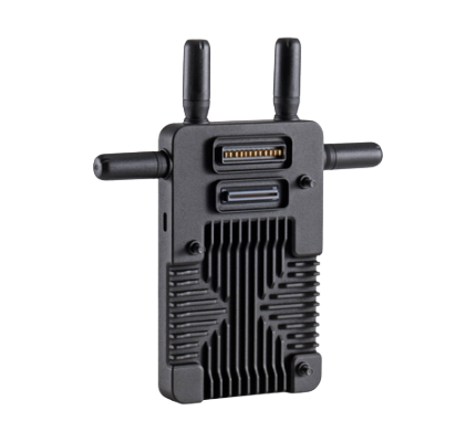 Close-up of a black electronic device with antennas and a barcode scanner, placed on a yellow surface.