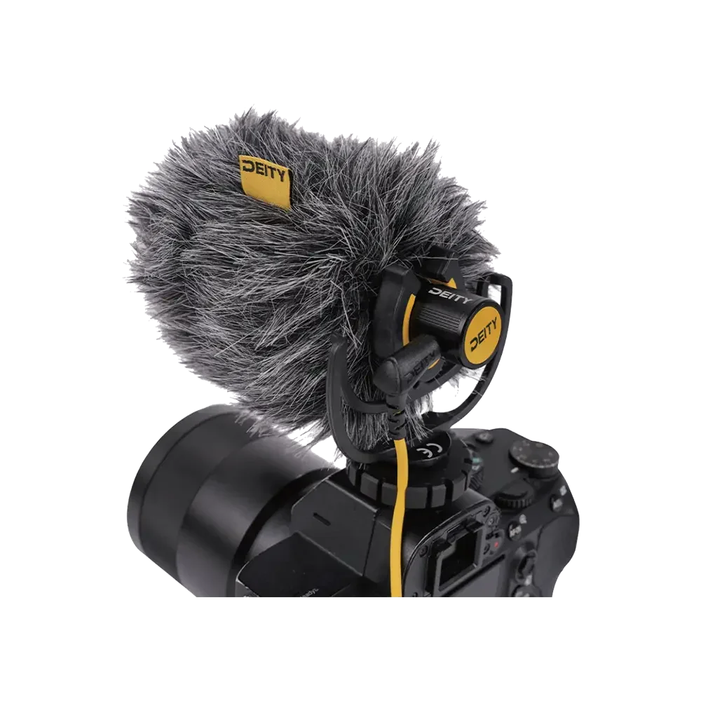 A professional camera with a large external microphone attached, featuring a furry windscreen cover, branded with 'Deity' in yellow and black colors.