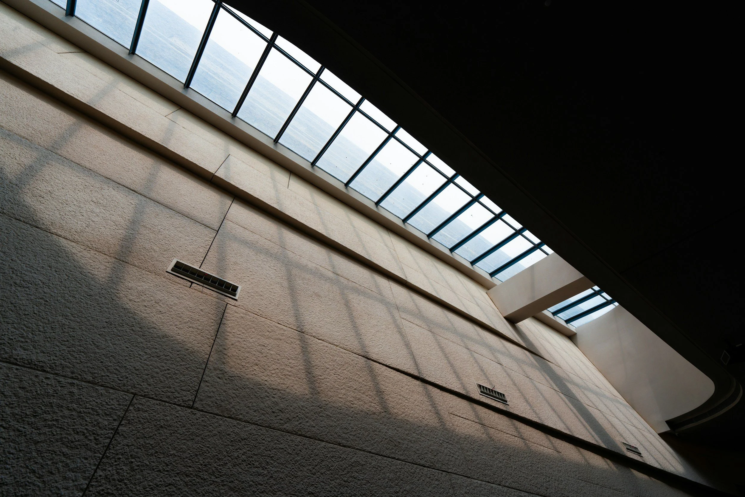 Interiör av en byggnad med en skyskrapeliknande glasöppning på taket, vilket ger ljus till väggarna.