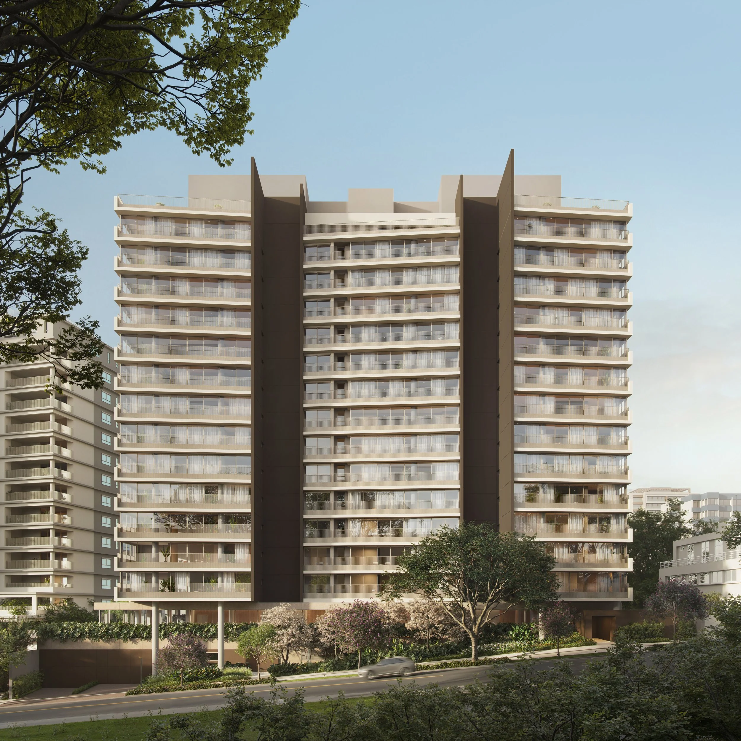 A modern multi-story residential building with many balconies, surrounded by trees and a street with a passing car, under a clear blue sky.