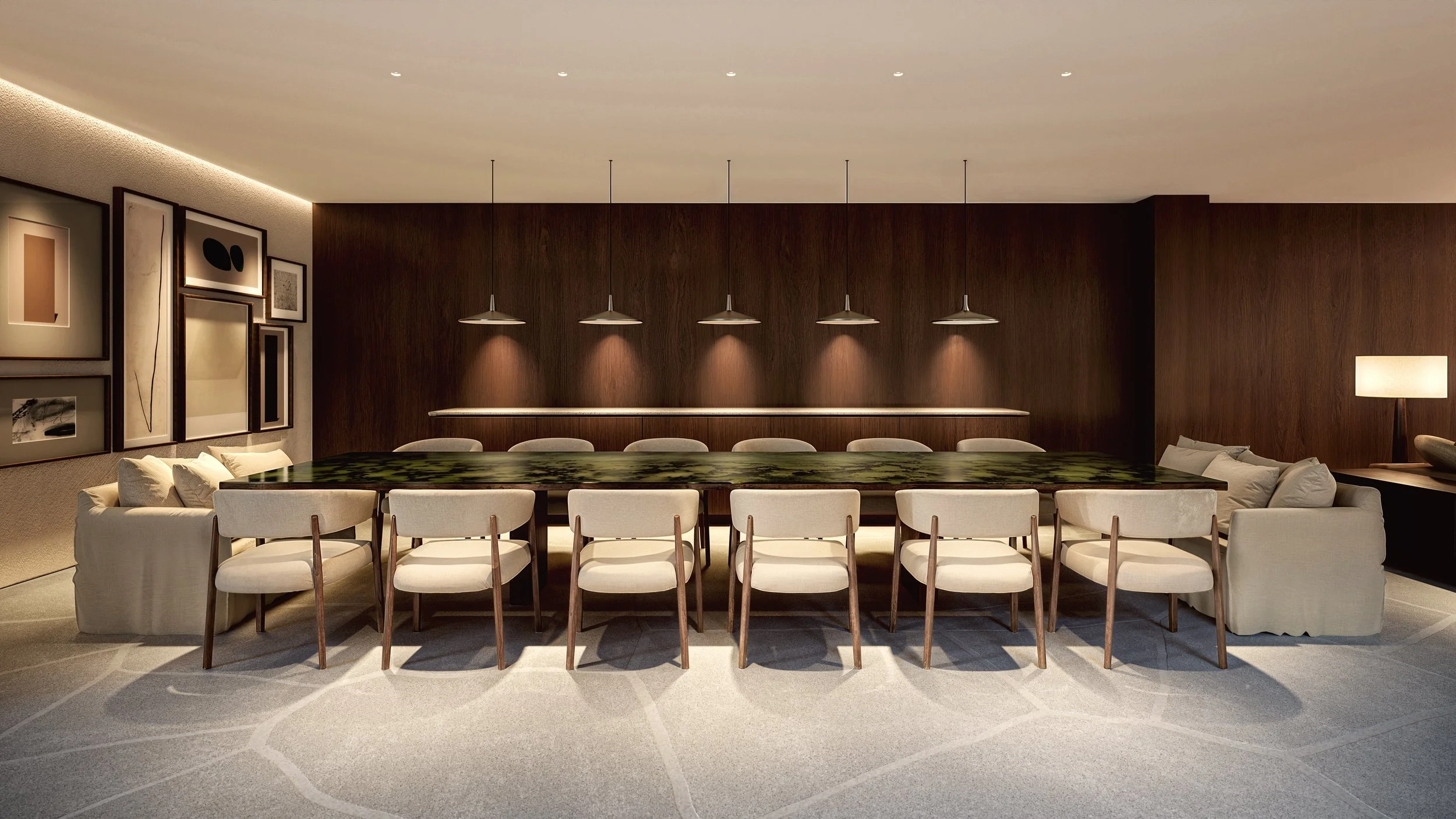 Modern dining room with a long dark wood table, multiple beige chairs, a beige sofa, abstract wall art, a table lamp, and warm lighting.