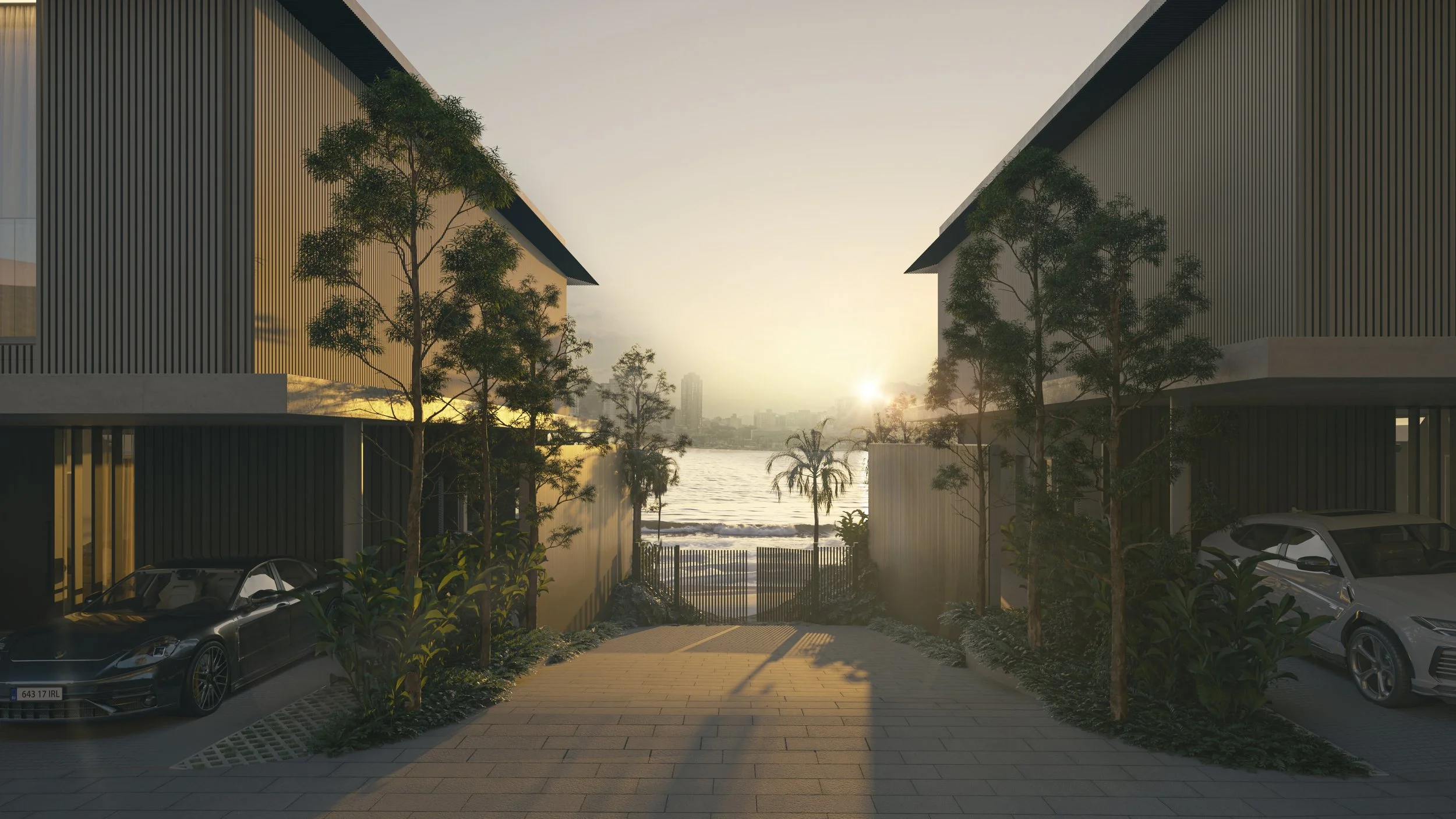 Modern residential buildings with a view of a river or lake at sunset, cars parked in driveways, trees and plants lining the pathway leading to a gate.