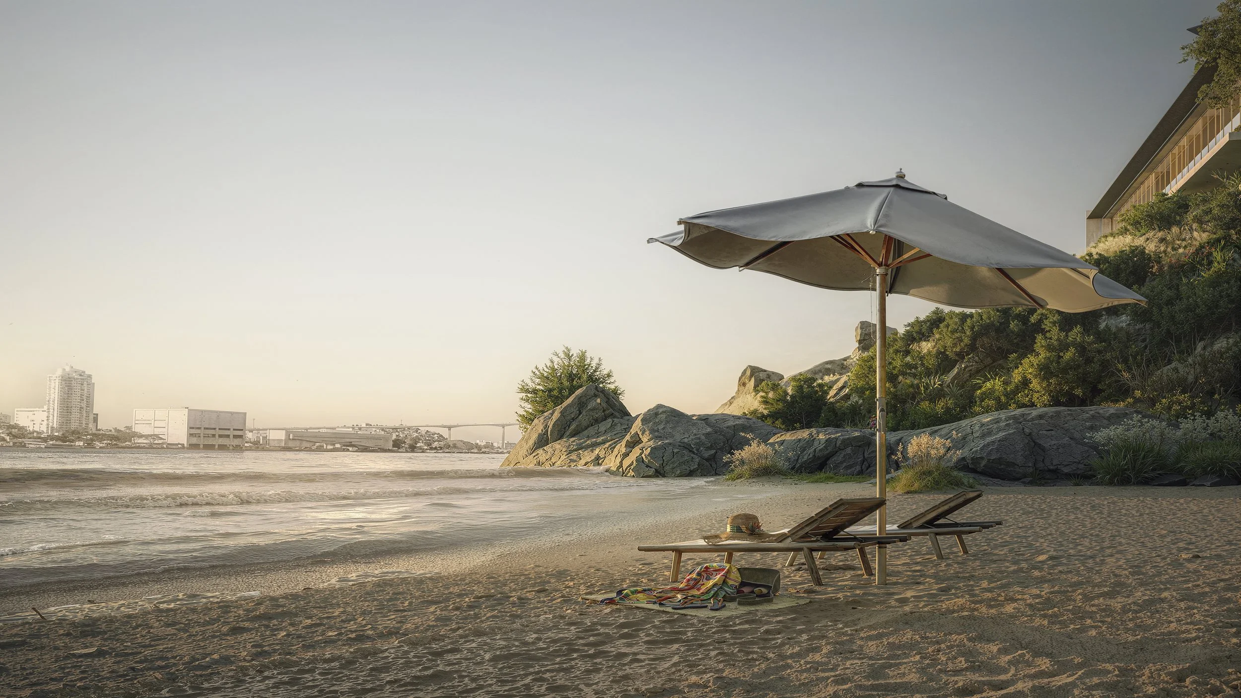 Empty beach with two lounge chairs, a large umbrella, and a hat with a towel on one of the chairs.