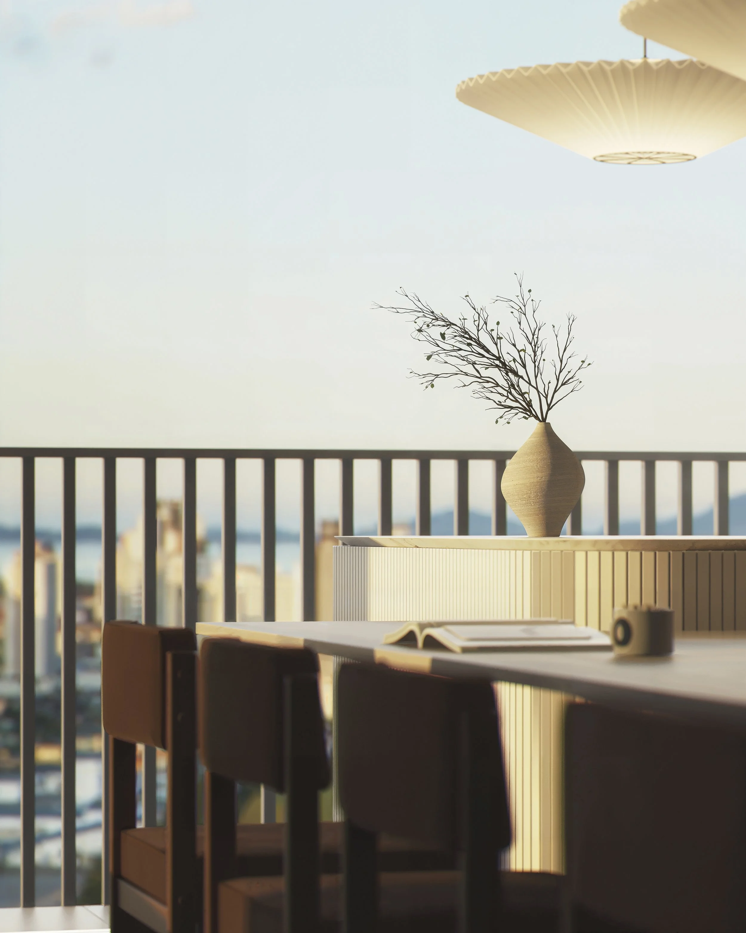 Interior view of a dining area with a wooden table, chairs, a open book, a white vase with a bare tree branch, a small object, and a large window showing an outdoor cityscape with mountains in the background, under hanging pendant lights.