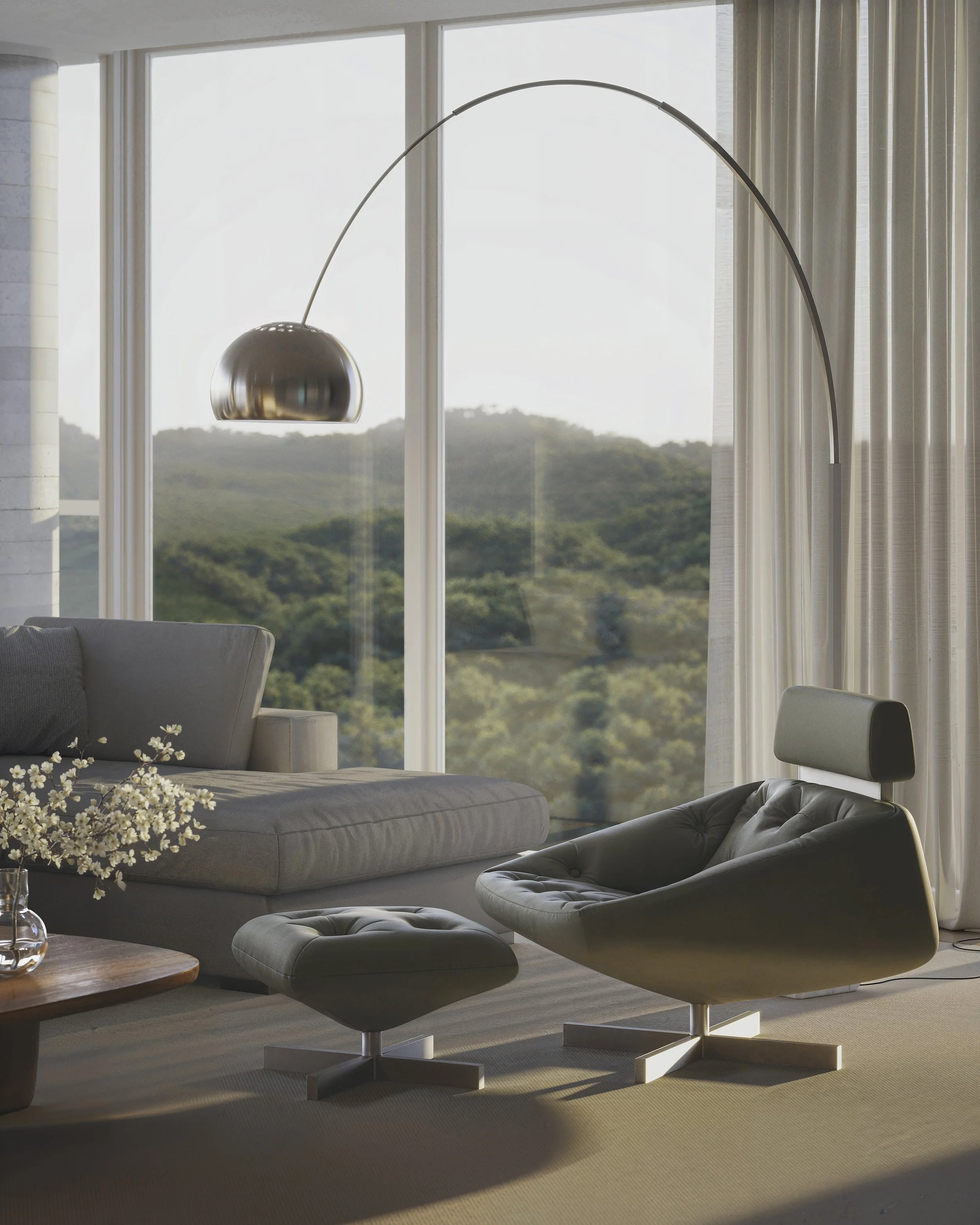 Modern living room with a gray sofa, matching ottoman, black lounge chair, and a floor lamp with a curved arm and metallic shade near large windows overlooking green hills.