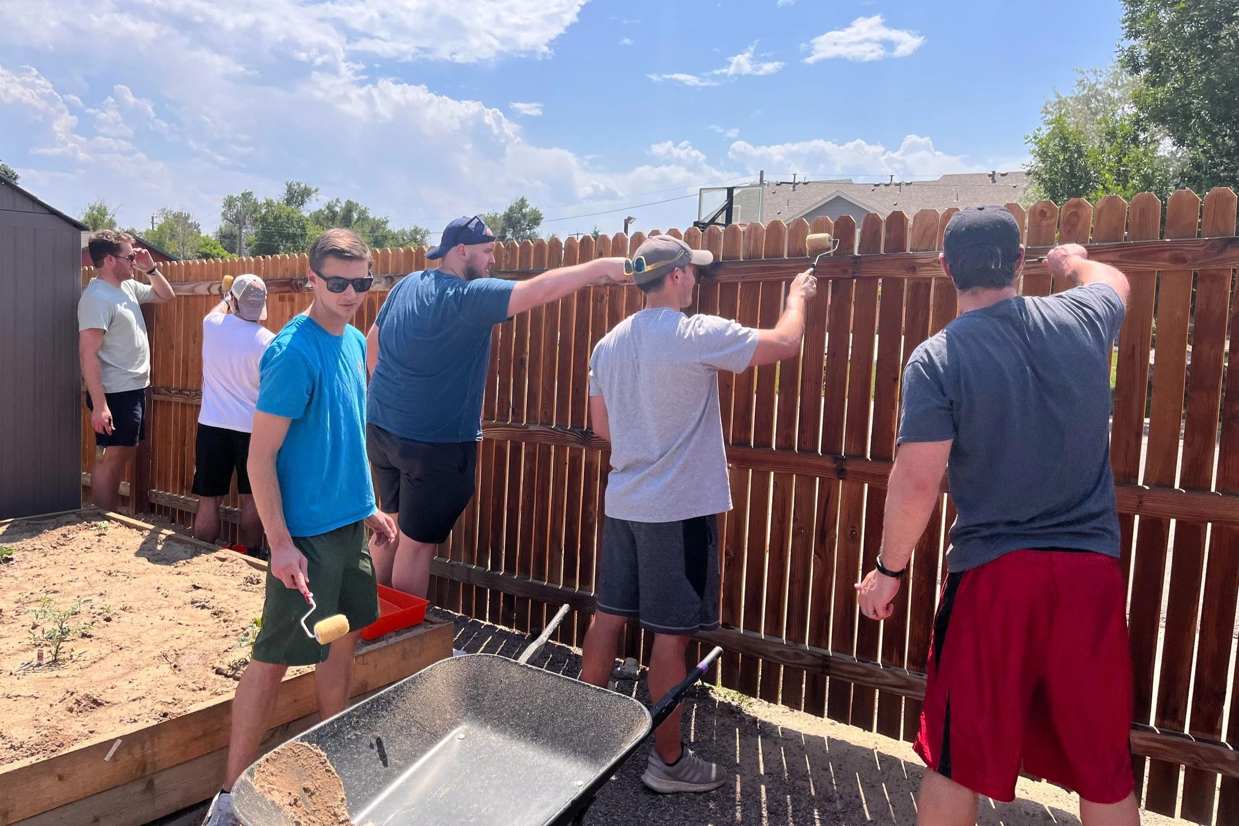 BeyondHome volunteers repairing and painting fencing in the BeyondHome community