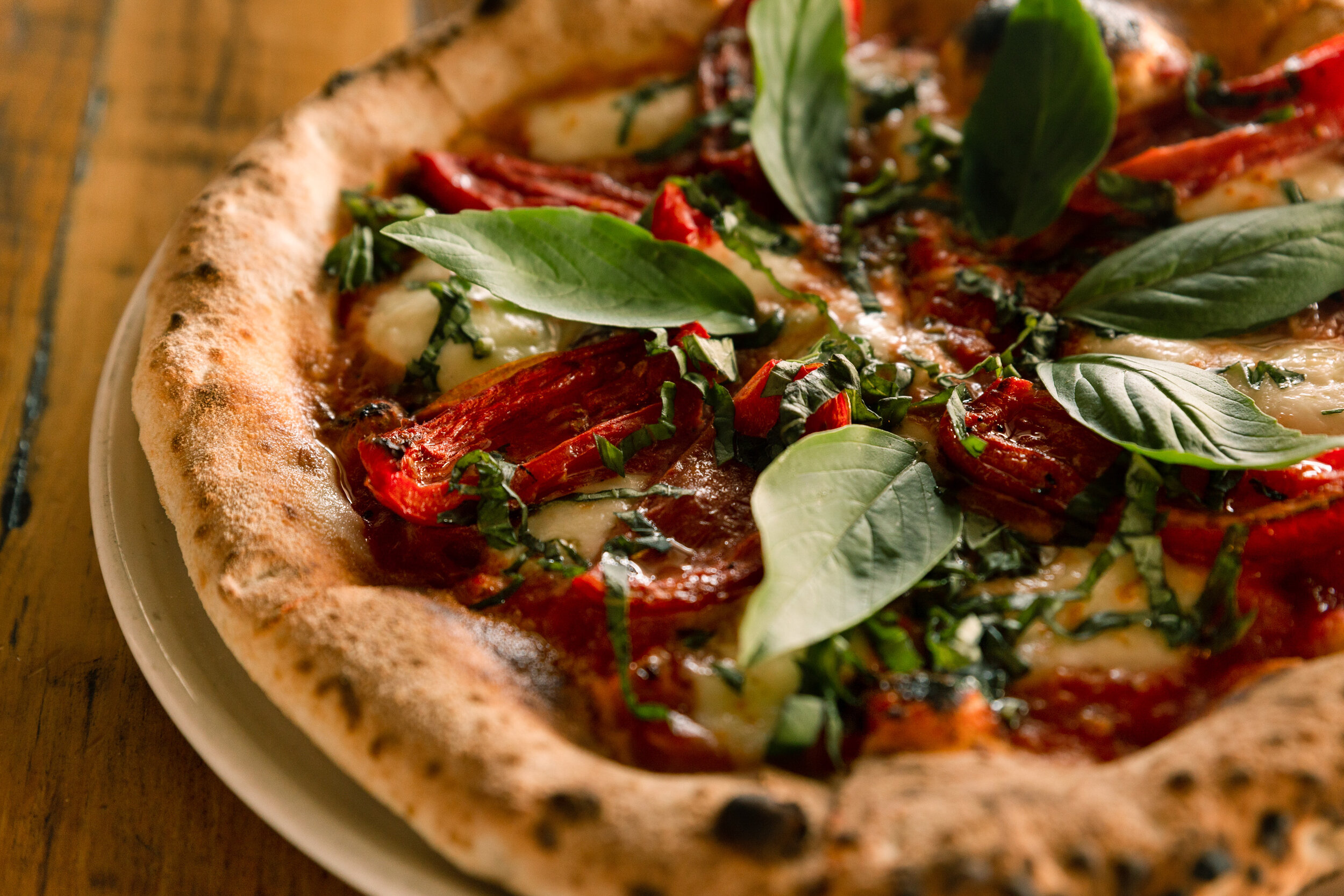 Woodfired margherita pizza topped with fresh basil.