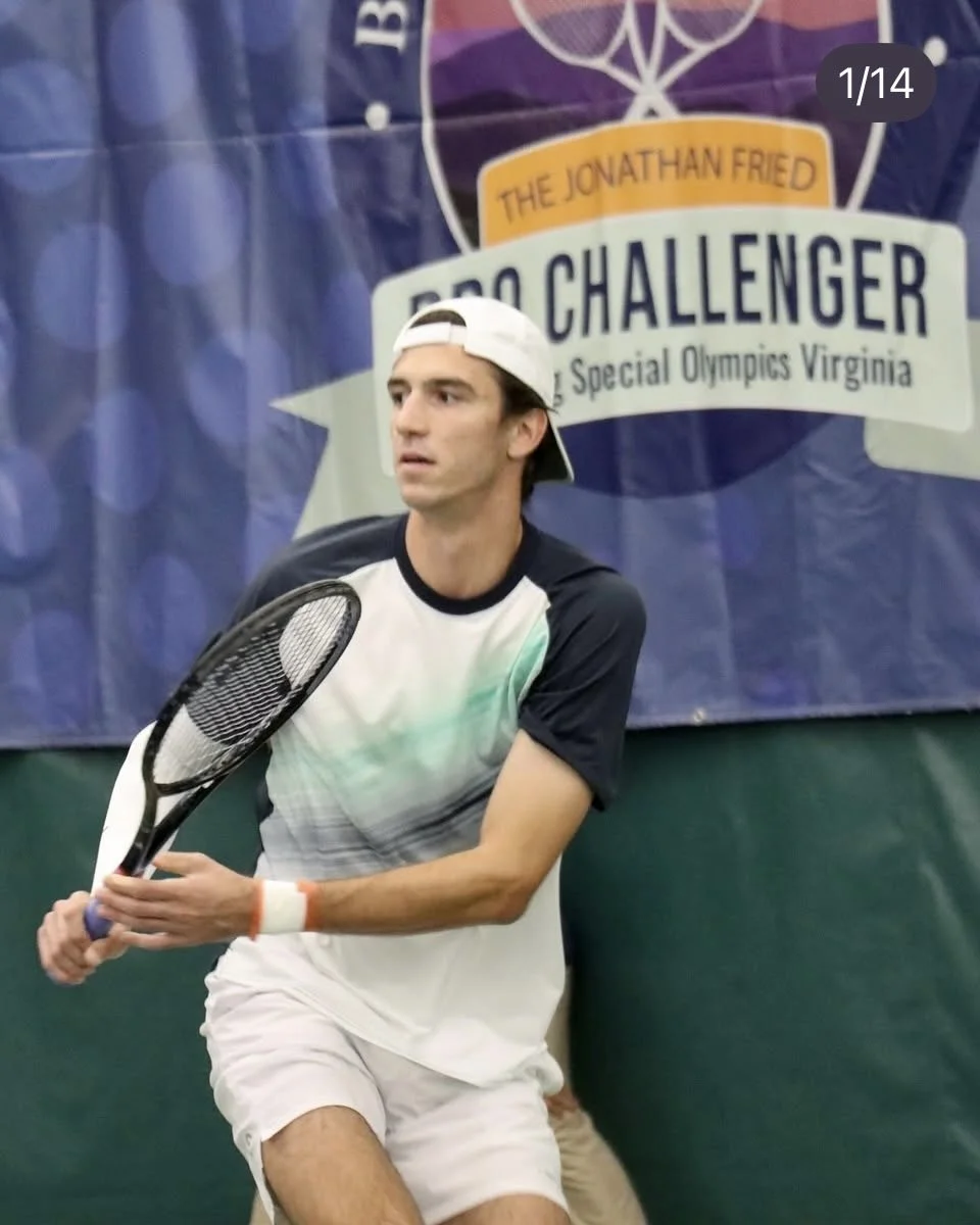 Dylan Dietrich beim Tennisspielen, trägt eine weiße Kappe, ein T-Shirt und Shorts, mit Tennisschläger in der Hand, im Hintergrund ein Banner mit dem Text "The Jonathan Fried BSC Challenger".