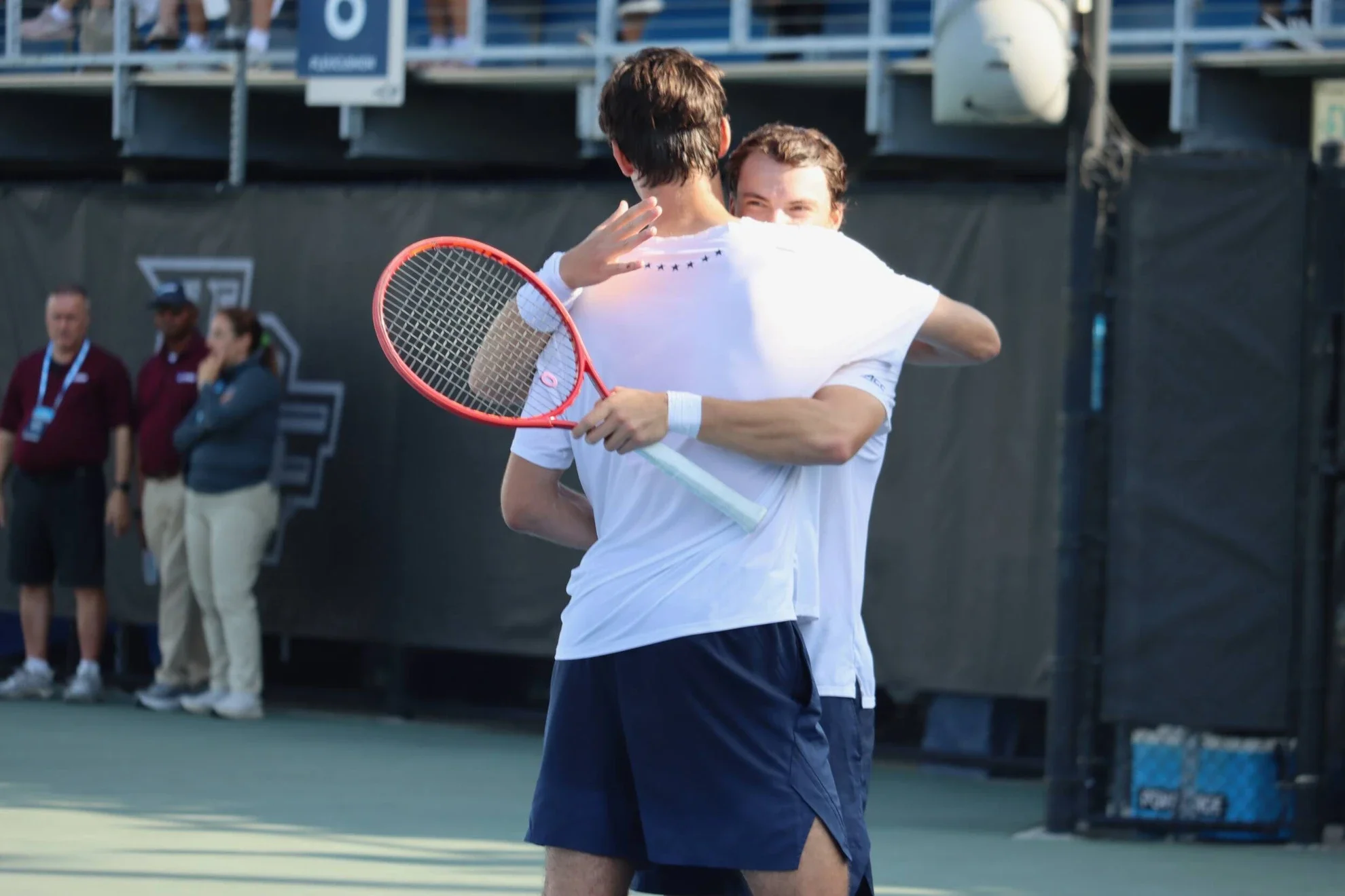 Zwei junge Männer beim Tennisspiel umarms sich auf dem Tennisplatz.