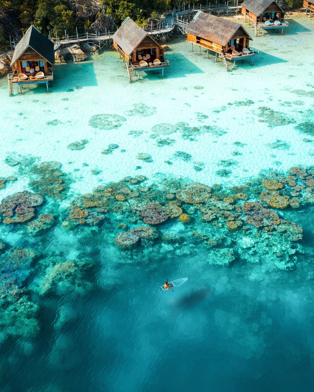 aerial_man_holding_oar_clear_kayaking_coral_reefs_lagoon_from_distance_west_overwater_suites.JPG