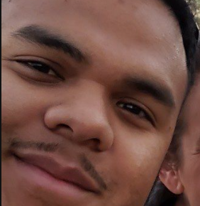 Close-up of a young man smiling with dark hair and dark eyes