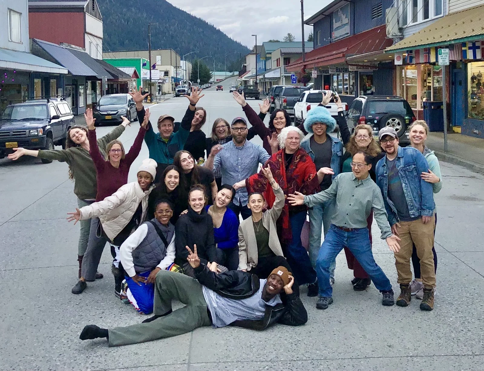 group of people pose with arms out in the middle of a street in rural alaska