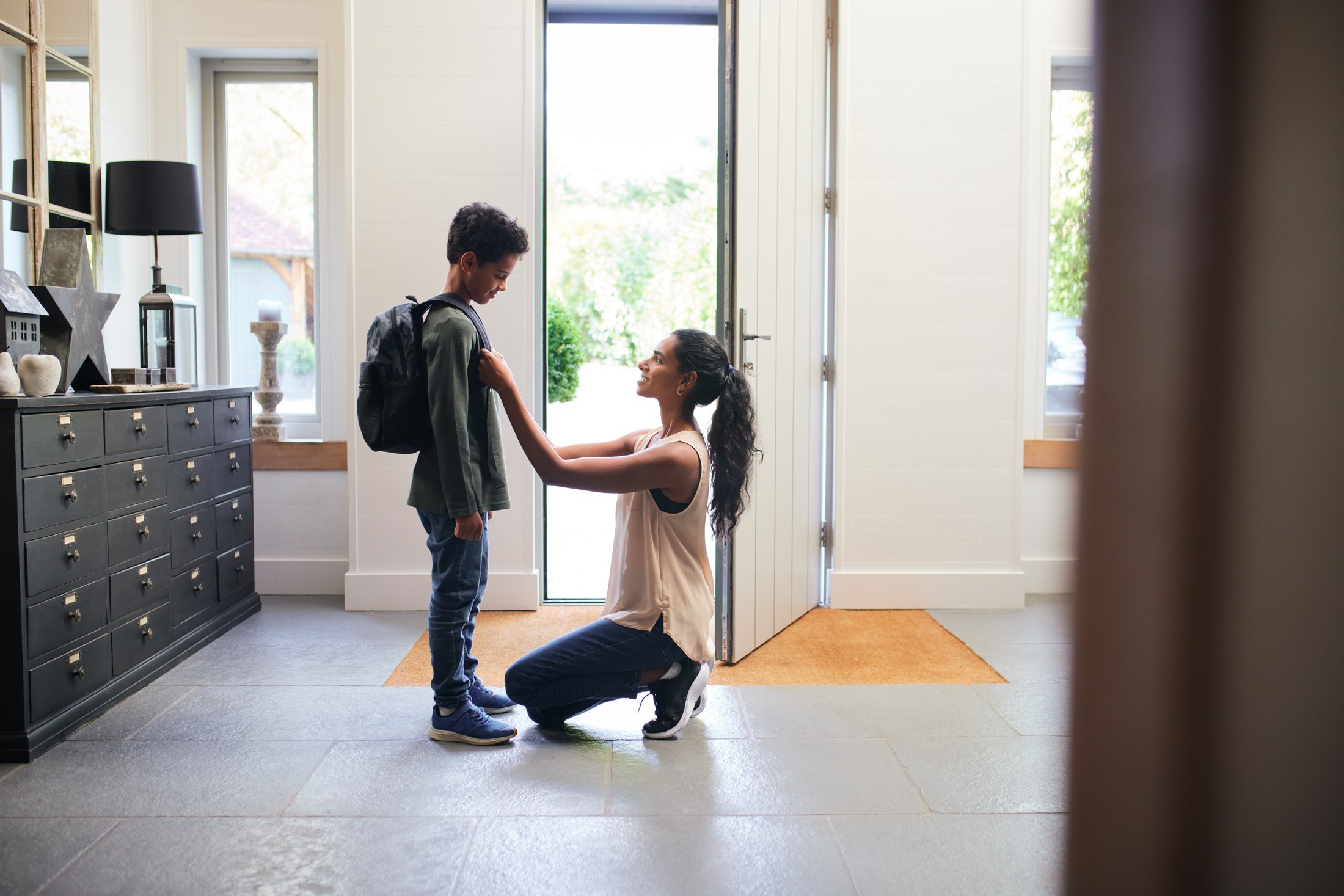 A child with a backpack coming through the front door to a parent kneeling with open arms to welcome them home because they knew where they were with the Protected Family Tier.
