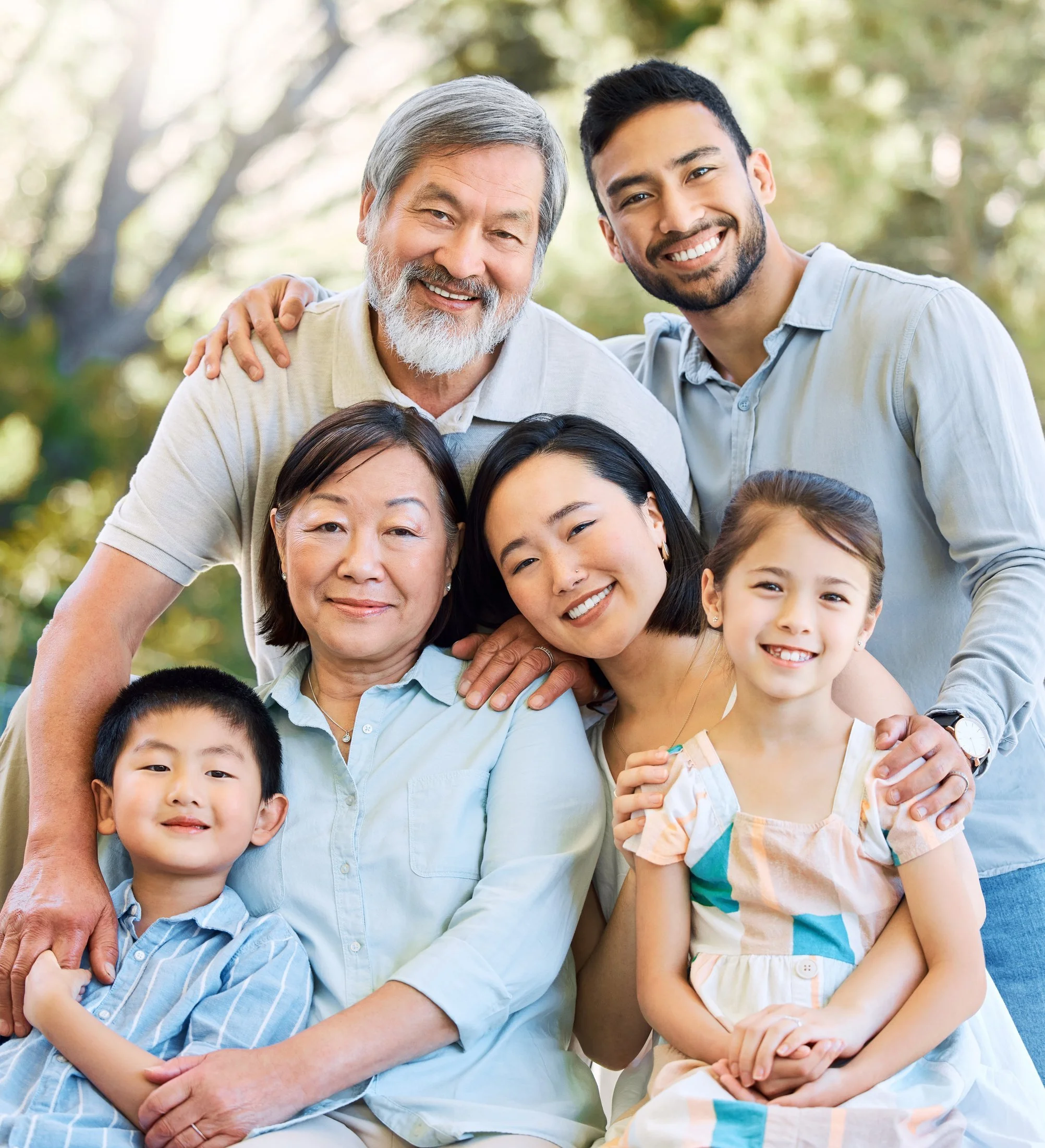 A joyful three-generation family — grandparents, parents and two young children — embracing together outdoors.covered by Protect Our Family Safety app