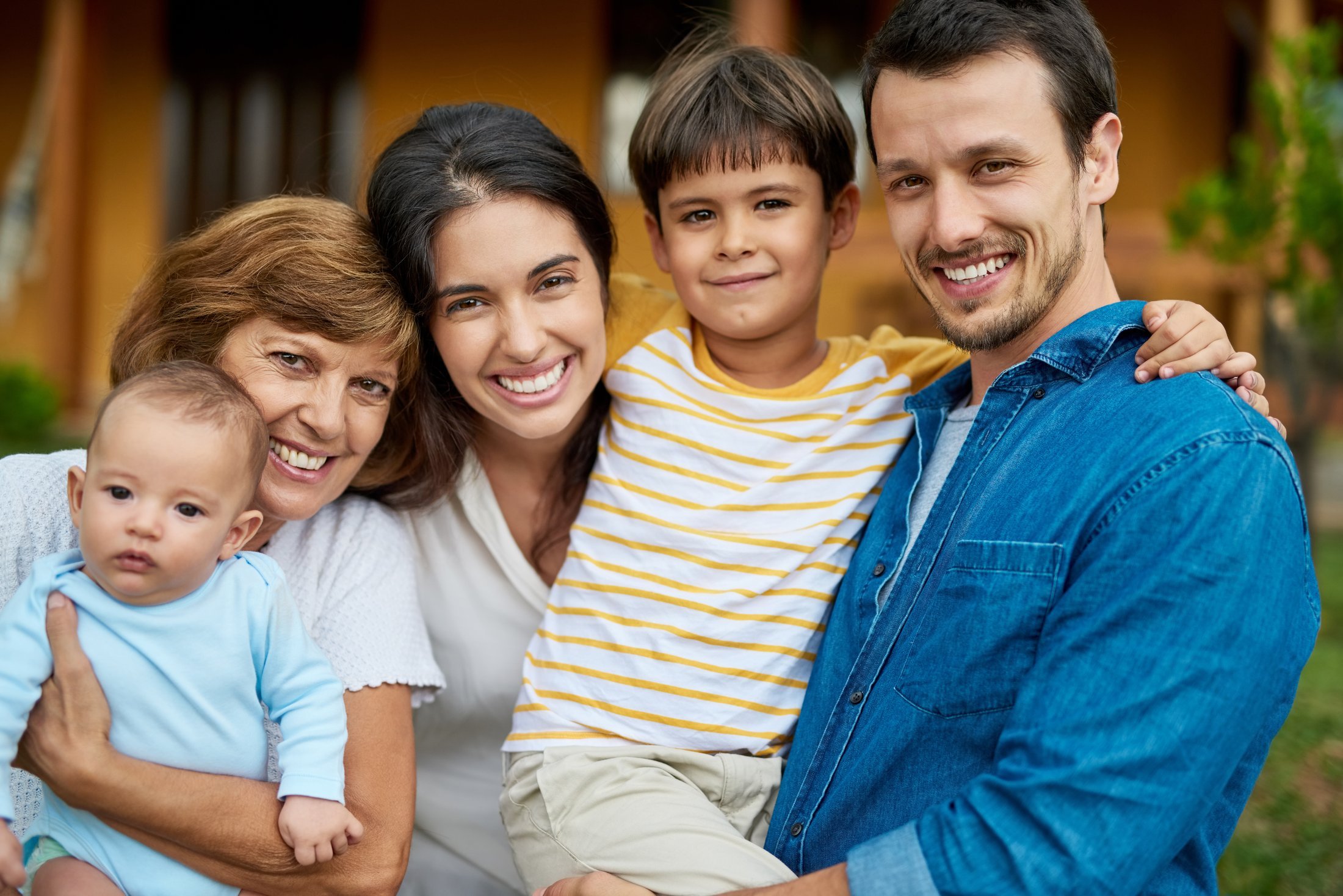A happy family — grandmother, parents and son — gathered close and smiling, ready and relaxed together. They joined Protect Our Family to have peace of mind.
