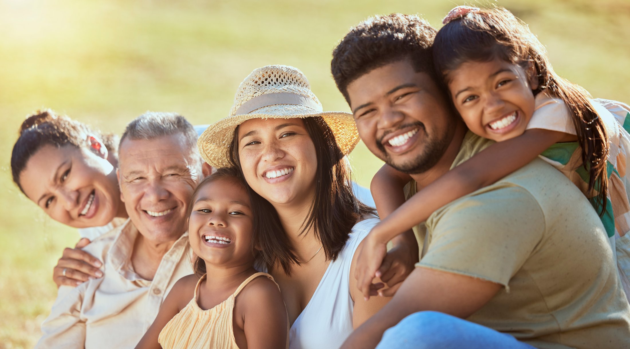A big multi-ethnic family laughing together at a garden picnic in the park. Enjoying the day stress free because everyone is protected.