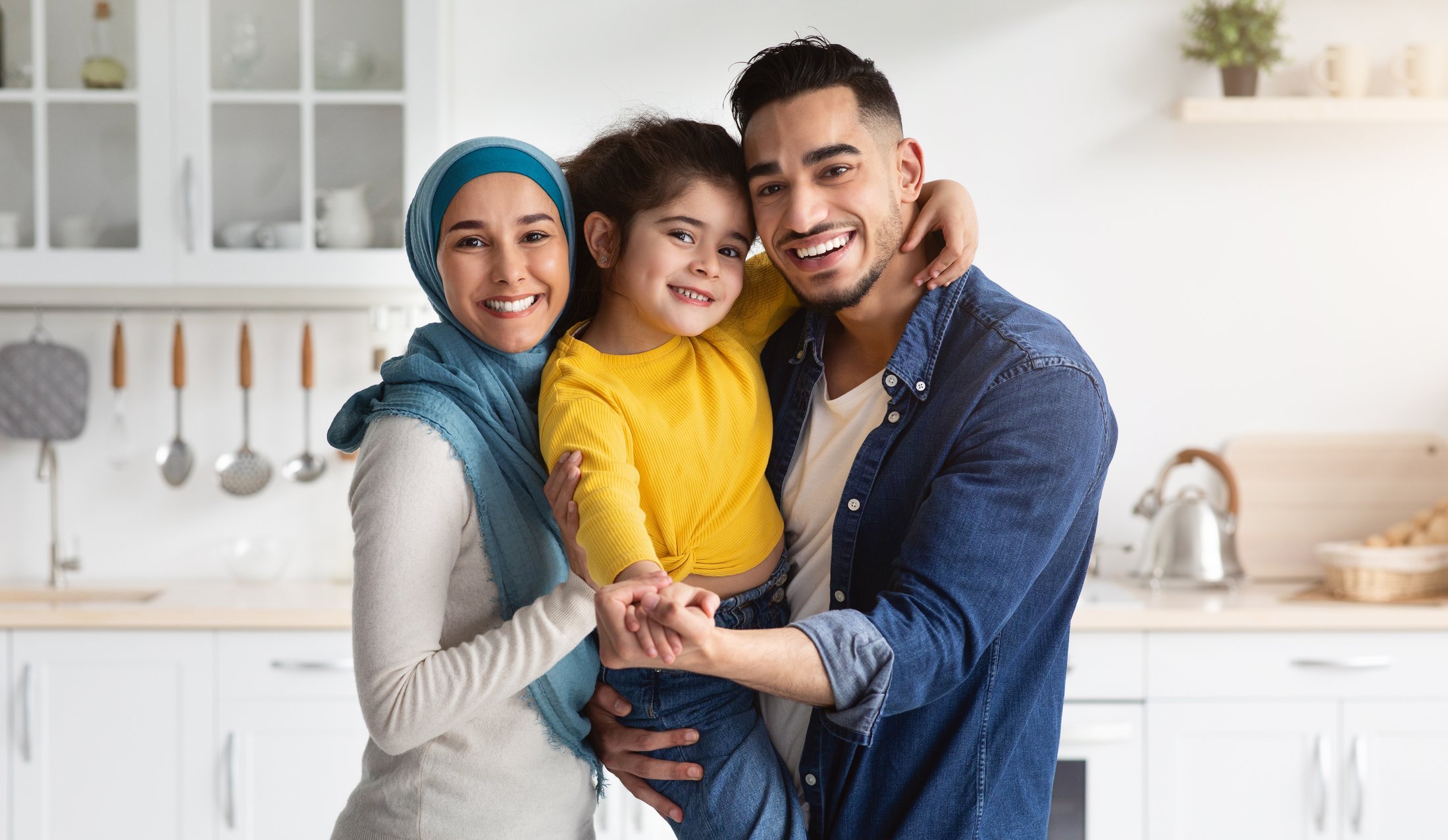 A family hugging and laughing together in a bright, homely kitchen. They aren't worried that their data is being sold.