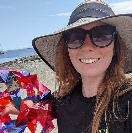 woman on a beach with hat holding mathematical sculpture