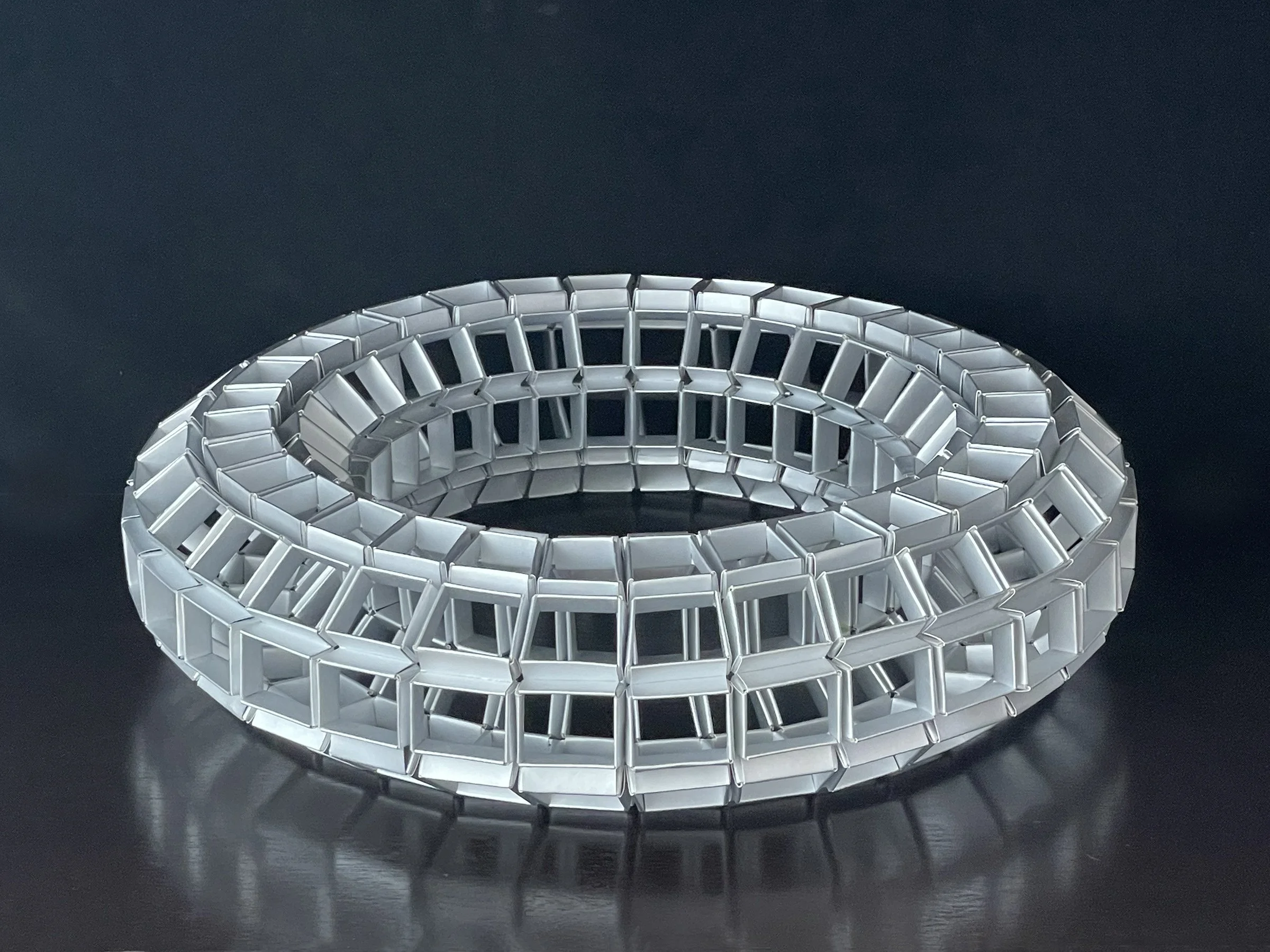 A coiled, metallic, expandable jewelry or storage bracelet on a black surface.