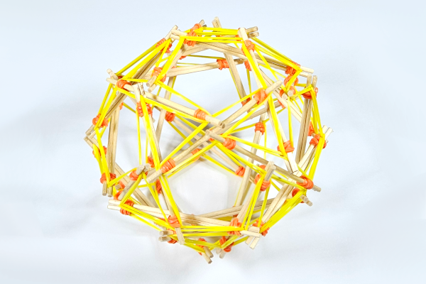 An intricate geometric structure made of wooden sticks connected with yellow plastic connectors, forming a complex polyhedral shape.