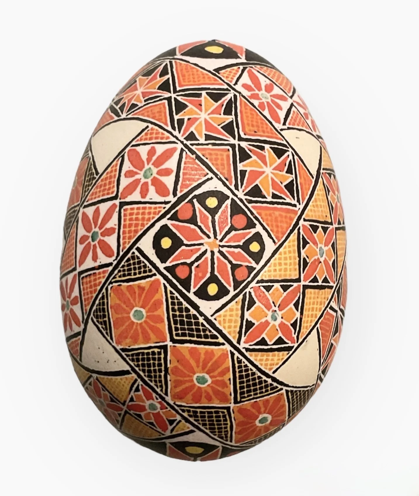 Decorative ceramic egg with geometric and floral patterns in orange, black, yellow, and green colors.