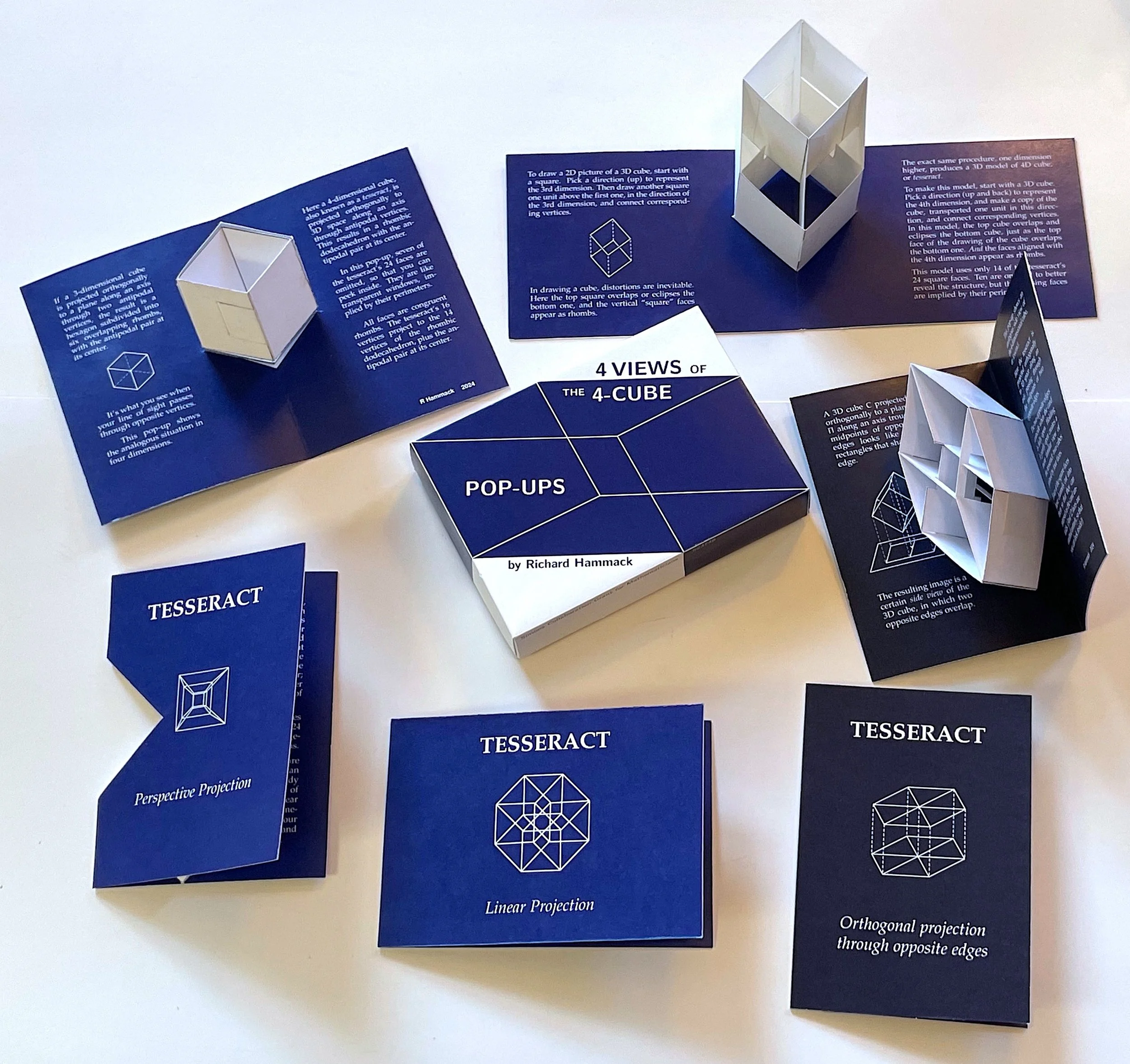 Set of blue and white educational paper booklets and a card about 3D geometric shapes, including cubes and tesseracts, with diagrams and descriptions, arranged on a white surface.